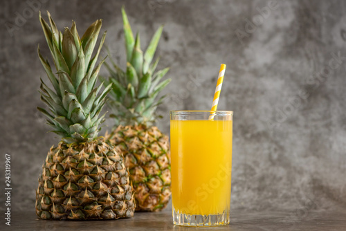 glass of pineapple juice with fresh fruits on grey bacground