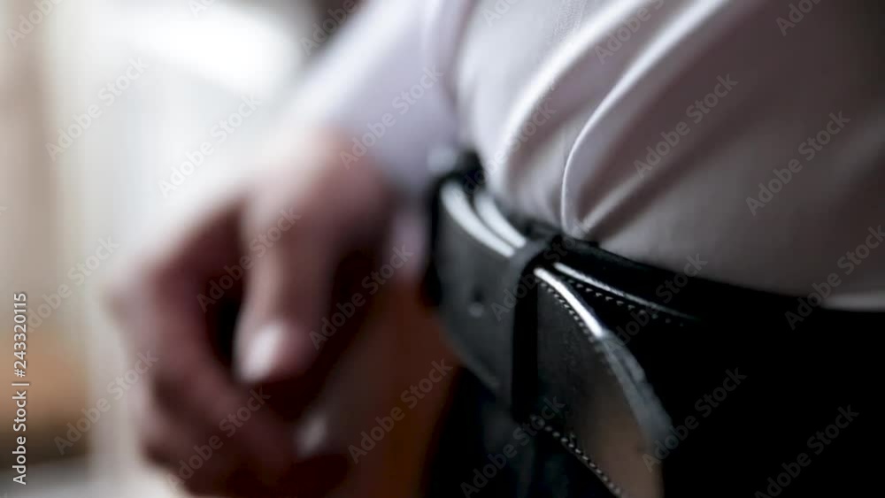 The young man corrects a belt on trousers. The young man corrects a belt on trousers.