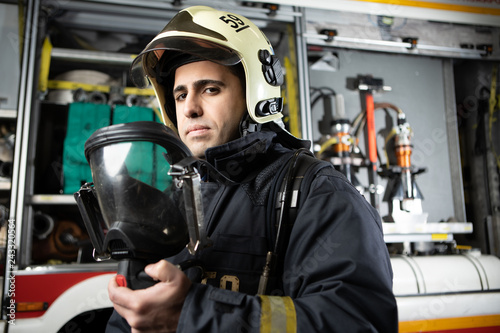Photo of fireman man in helmet at fire truck