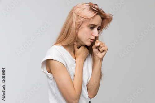 Cropped studio portrait of young unhealthy coughing woman holding her throat/suffers from cold and flu, coughing a lot, sore throat, feeling sick, chest pain, medicine and healthcare concept.