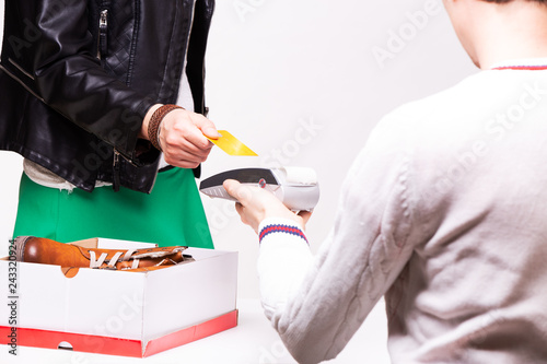 Woman buys shoes at the shop checkout, she is paying using a credit card.