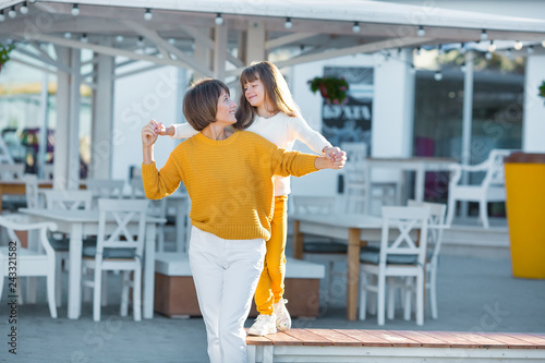 Mother and little daughter having fun in a park on a nice sunny day.wearing casual clothes yellow and white color