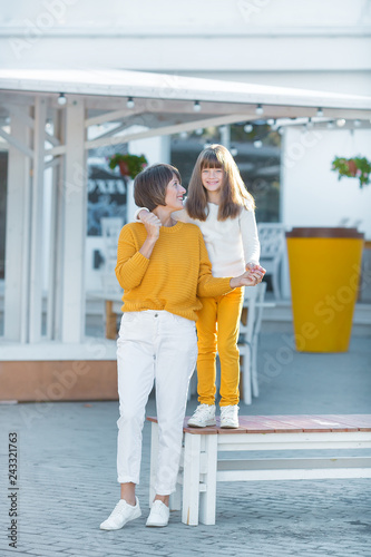 Mother and little daughter having fun in a park on a nice sunny day.wearing casual clothes yellow and white color