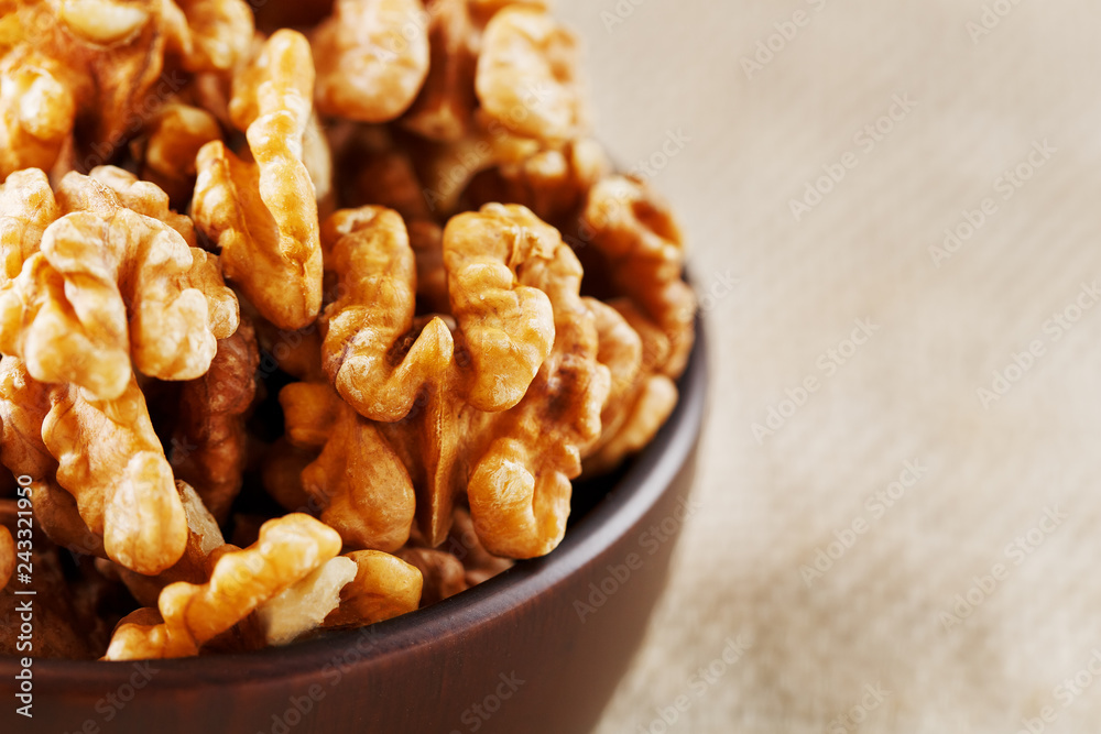 Peeled walnuts in a wooden, dark brown cup on a burlap cloth. Peeled walnuts in a wooden, dark brown cup on a burlap cloth.