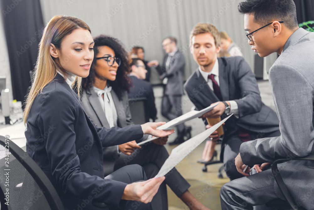 young business people holding papers and discussing project in office