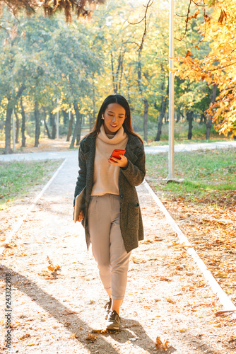 Smiling young asian woman wearing coat walking