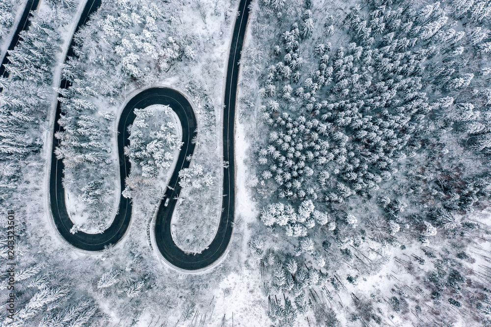 winter winding road in the forest aerial view from a drone