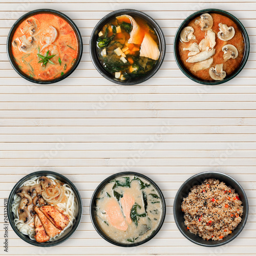 Delicious Asian dishes in black bowls. Wooden background with copy space.