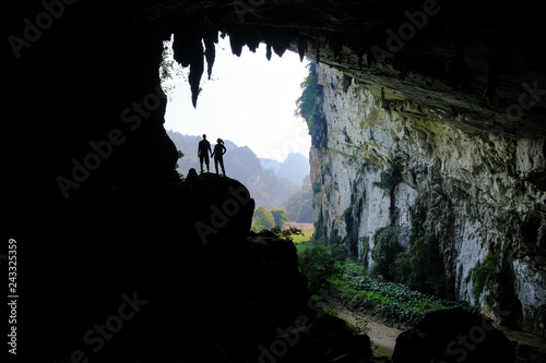 Ba Be Lakes / Vietnam, 03/11/2017: Silhouettes of two people standing in a rocky outcrop inside a giant cave in the North Vietnamese Ba Be lakes region.
