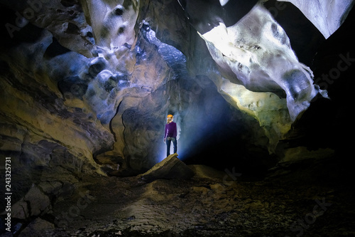 Backlit woman standing  on a rock inside the Hang Tien cave in the Phong Nha Ke national park in Vietnam.