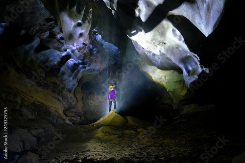 Backlit woman standing  on a rock inside the Hang Tien cave in the Phong Nha Ke national park in Vietnam.