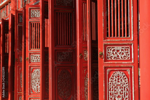 Red ornamental doors in a traditional pavillion in the Citadel complex in Hue, Vietnam.