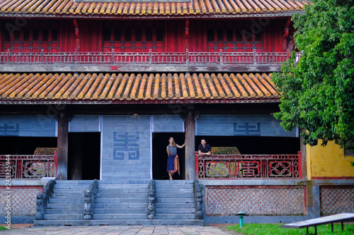 Couple standing inside a traditional house with ornamental tiled roof in the Citadel of Hue, Vietnam.