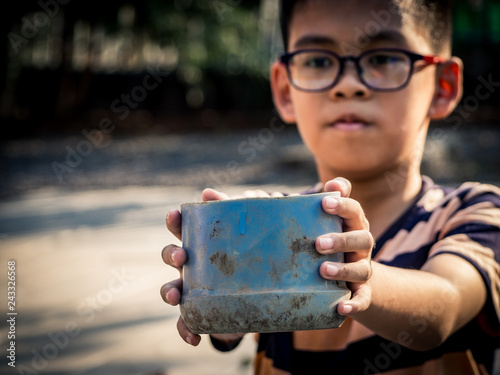 Εκτύπωση καμβά Child homeless holding plastic bowl with hungry and need food from traveler on street at the city
