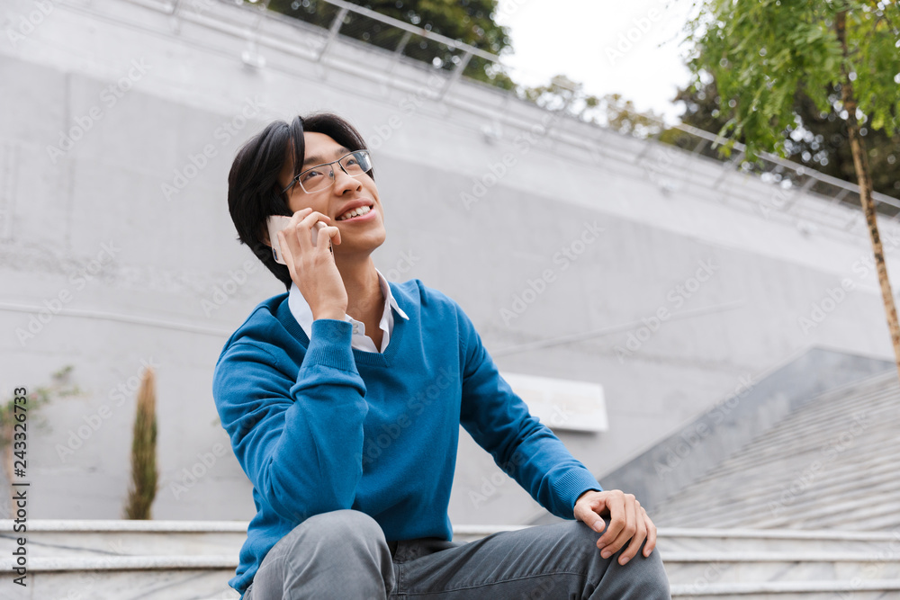 Smiling young asian man talking on mobile phone