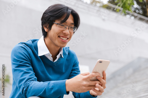 Smiling young asian man talking on mobile phone
