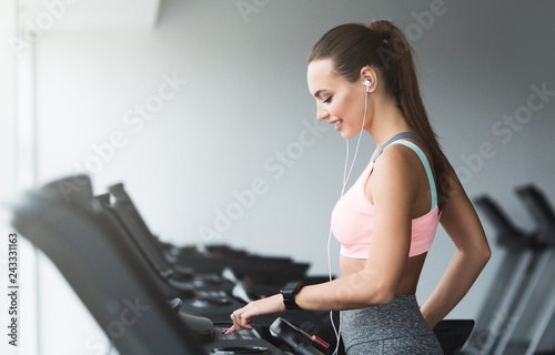 Woman adjusting speed on treadmill, doing cardio workout