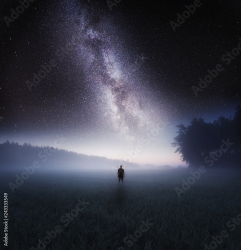 Dreamy surreal landscape with starry night sky and man silhouette