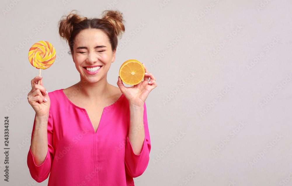 Happy woman with lollipop and orange over background Happy woman with lollipop and orange over background