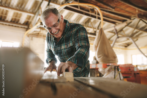 Smiling mature man working in carpentry workshop photo