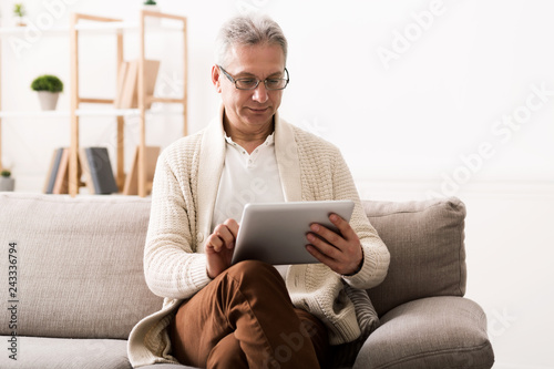 Mature man reading news on tablet at home