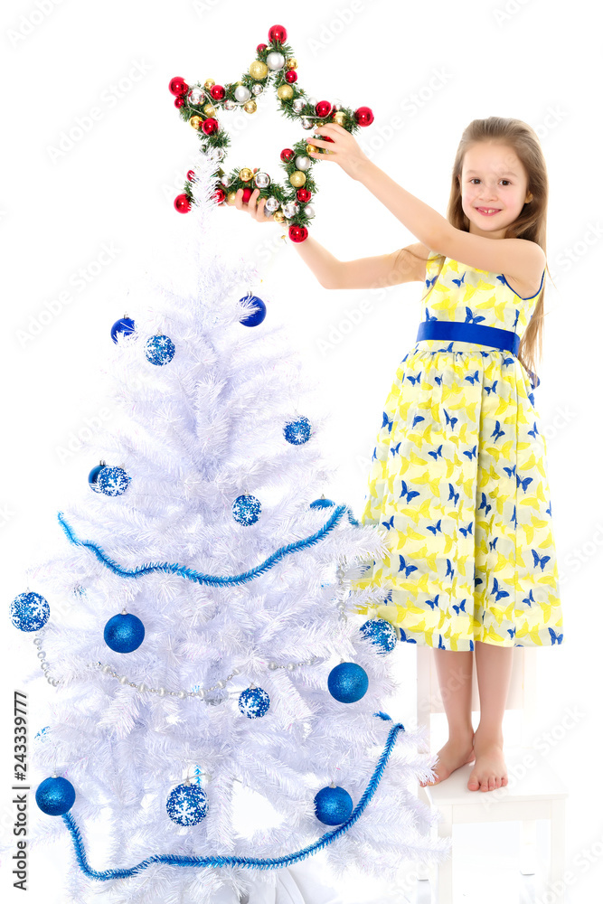 A little girl is decorating a Christmas tree.