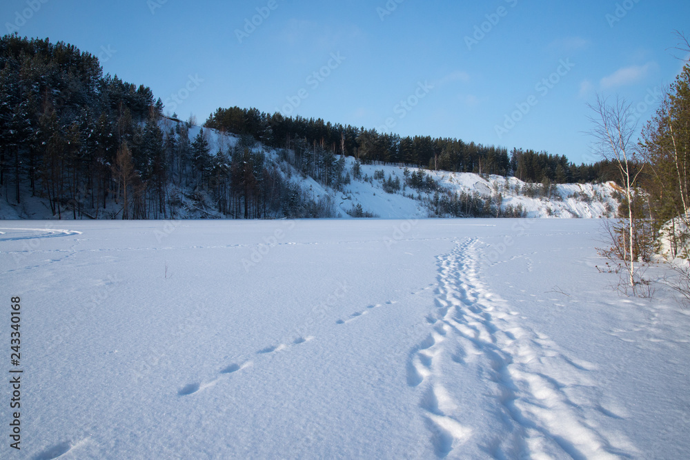 Sunny weather. Path on a snowy lake.