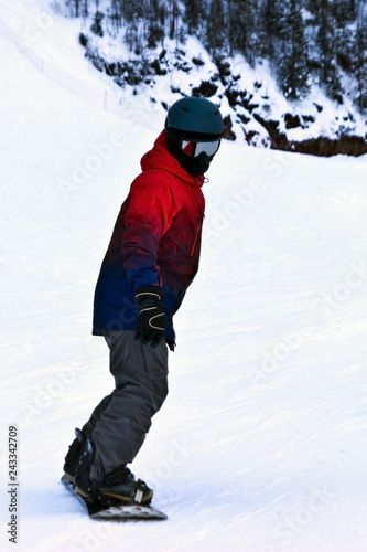 rear view of a sportsman riding a mountain on a snowboard