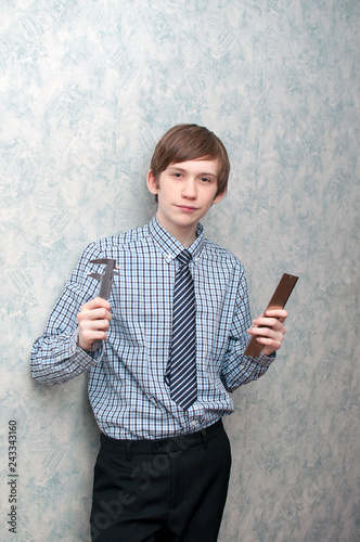The young Russian guy holds a caliper and a metal ruler in hand.