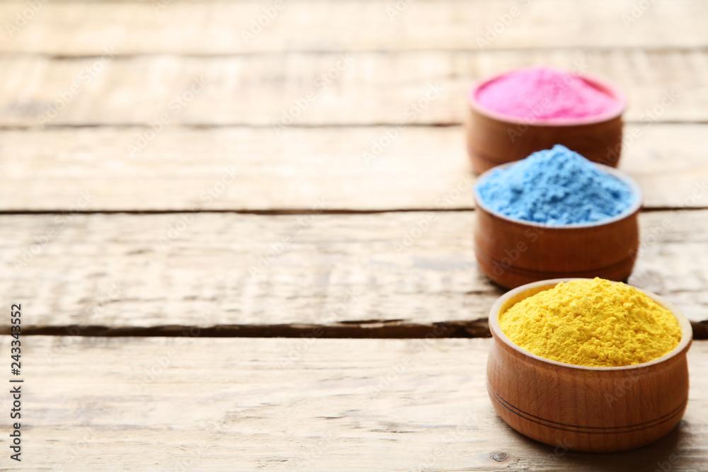 Colorful holi powder in bowls on brown wooden table Colorful holi powder in bowls on brown wooden table