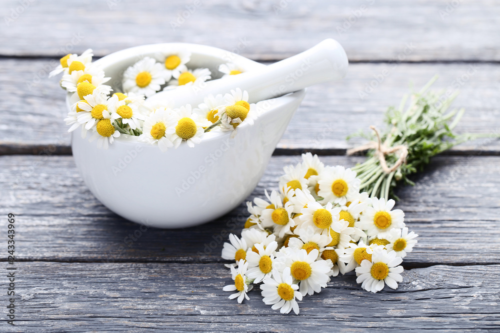 Chamomile flowers in mortar on grey wooden table Chamomile flowers in mortar on grey wooden table