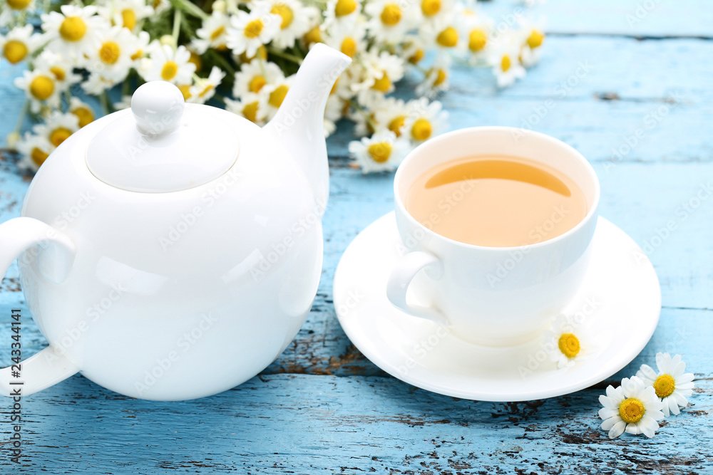 Cup of tea with chamomile flowers on blue wooden table Cup of tea with chamomile flowers on blue wooden table