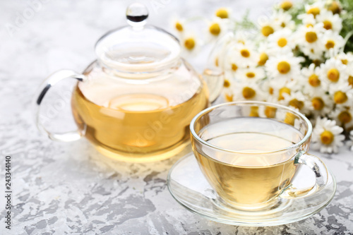 Cup of tea with chamomile flowers on grey background