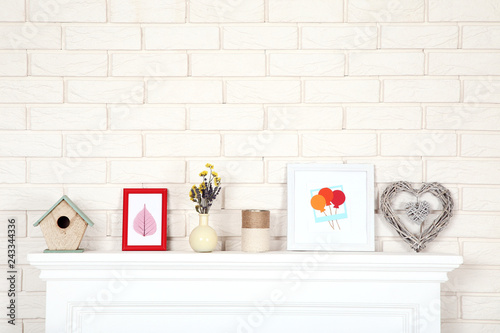 White fireplace with photo frames, nesting box and flowers in vase