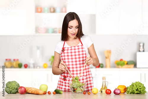 Beautiful woman cooking salad in the kitchen
