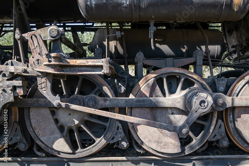 Old rusty wheels of the steam locomotive and the elements of the drive