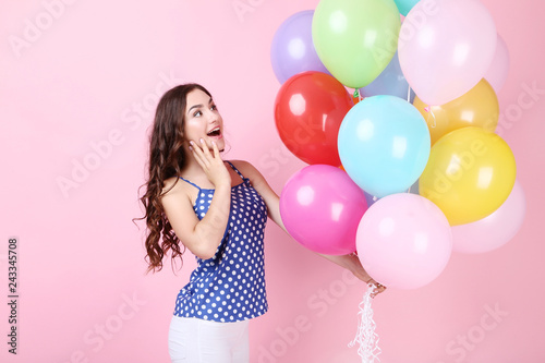 Young girl with colored balloons on pink background