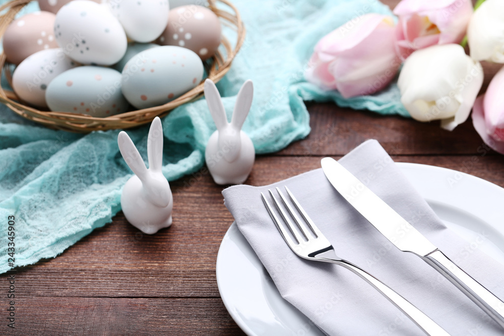 Kitchen cutlery with easter eggs and ceramic rabbits on wooden table