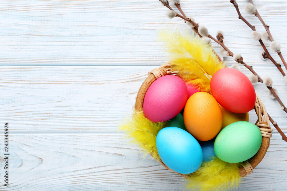 Colorful easter eggs in basket on wooden table