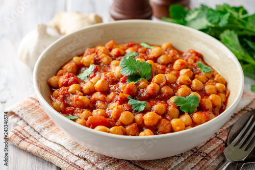 Spicy Chickpea curry Chana Masala in bowl on wooden table. Traditional Indian dish. Selective focus.