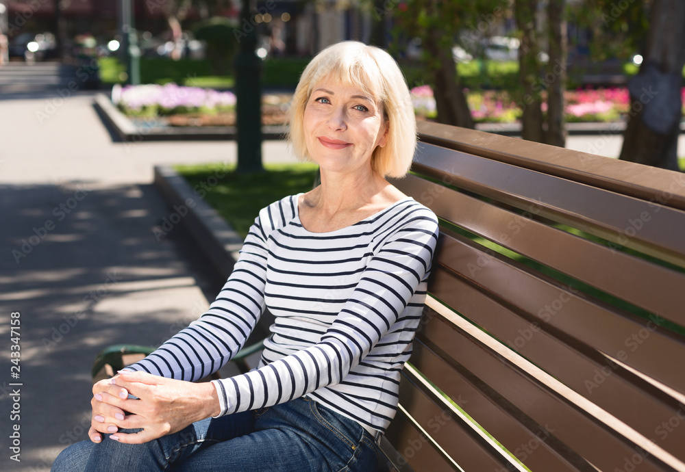 Senior woman relaxing on bench in city park Senior woman relaxing on bench in city park