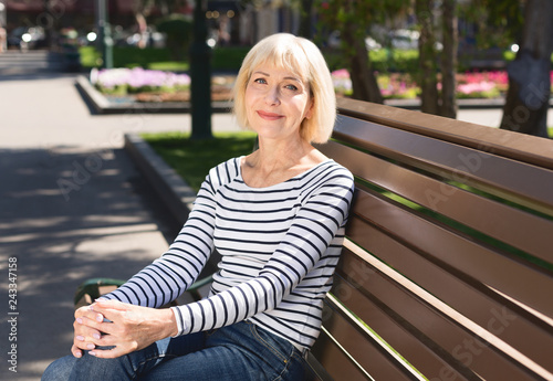 Senior woman relaxing on bench in city park