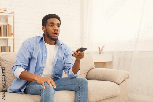 African-american man watching tv at home, copy space © Prostock-studio