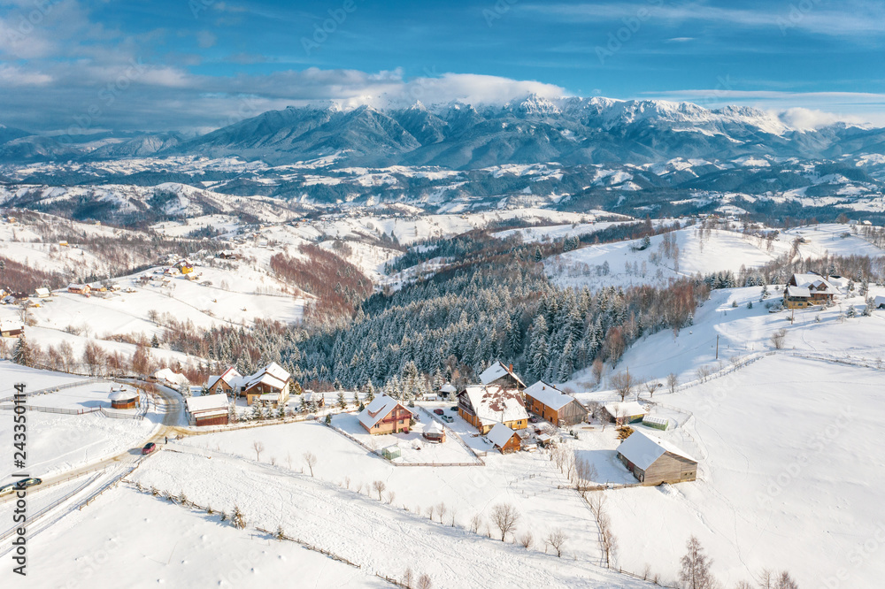 Winter in Romania with the Carpathian Mountains visible in the back and Pestera traditional village in the foreground