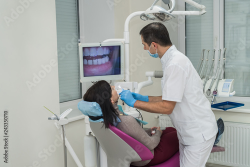 Dentist examining patient s teeth with intraoral camera