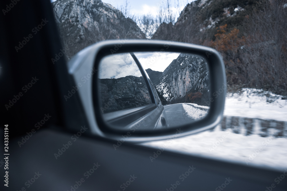 Rearview mirror of a car in a snowed road at winter, south of france