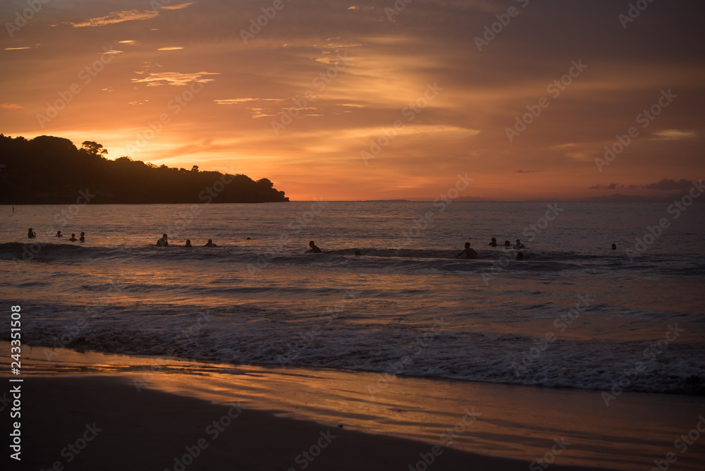 People swimming in the ocean during sunset