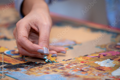 Adult and child solving a jigsaw puzzle on a table. 