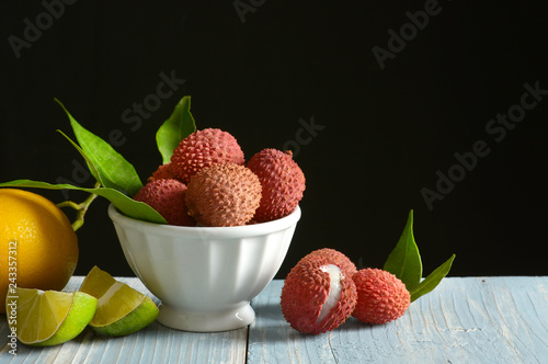 lychees fruits in the white bowl with citrus fruit around