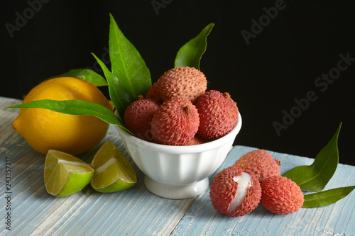 lychees fruits in the white bowl with citrus fruit around